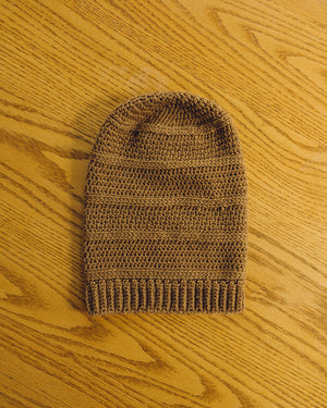 A Kinsol Trestle Toque, the colour of brown sugar, viewed from above, flat on a wood table